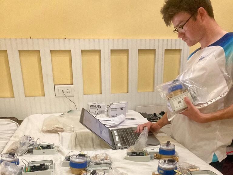 Matthew sits at a laptop surrounded by wires and other computer parts