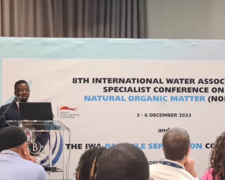 Samuel Nyarko stands at a lectern delivering a conference presentation