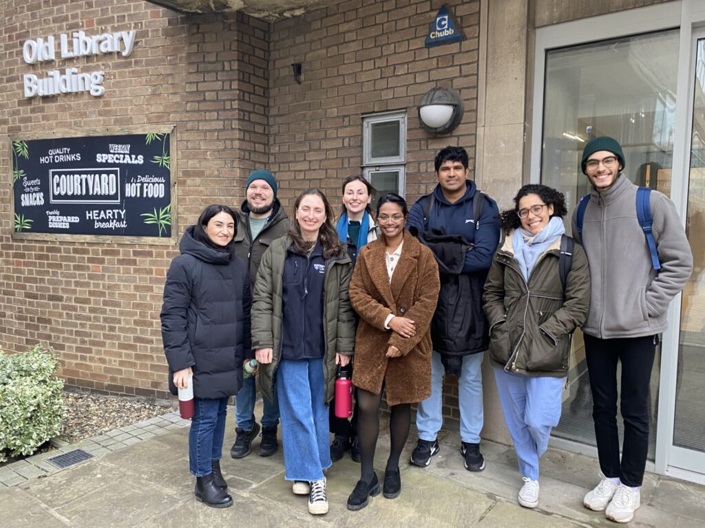 A group of WIRe CDT PhD students smiling at the camera in front of a building
