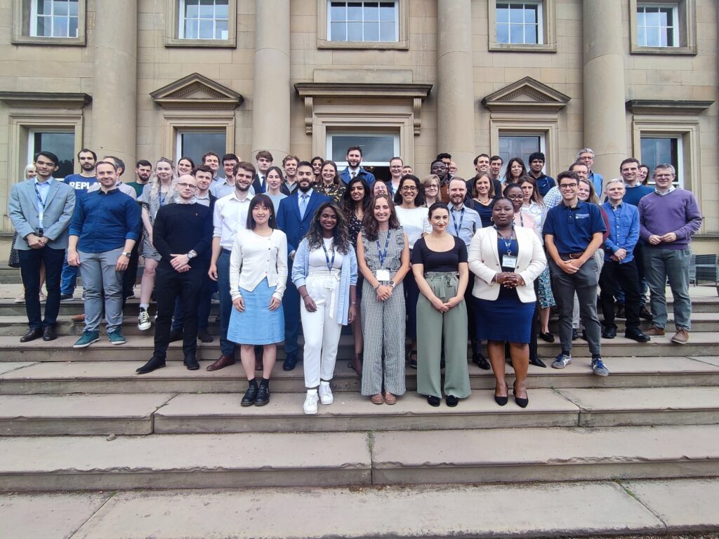 WIRe PhD students and staff stood on steps in front of a building smiling at the camera