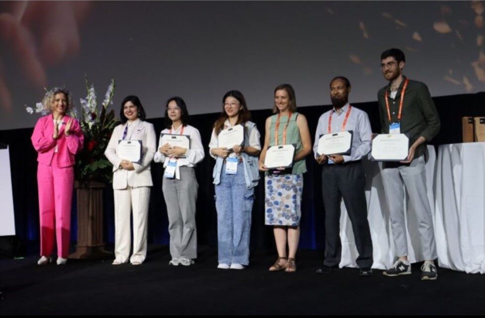 Several people stand on a stage holding certificates