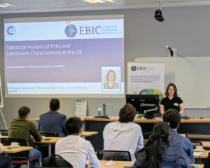 Emily stands at the front of a classroom delivering a presentation