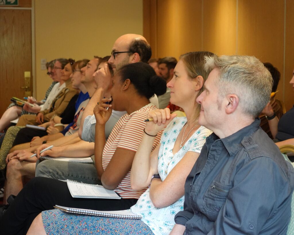 People sat in rows in an audience listen to a speaker out of shot