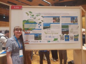 A woman stands in front of a scientific poster titled' Urban Trees and Flood Resilience: Monitor, Evaluate and Optimise'
