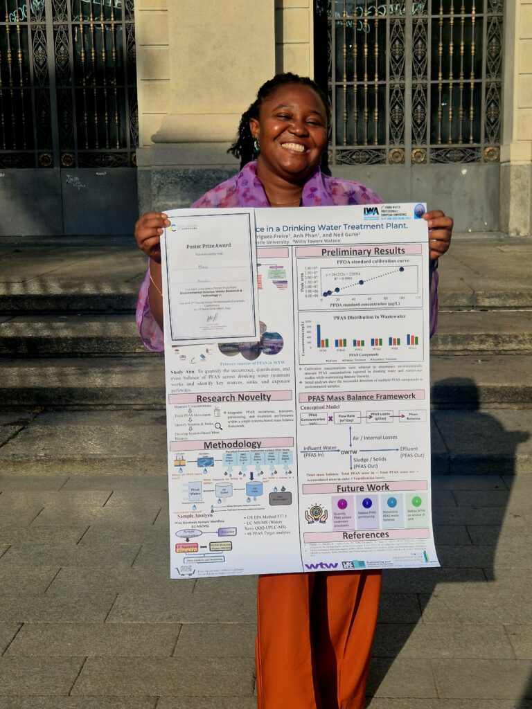 a woman smiles holding a scientific poster