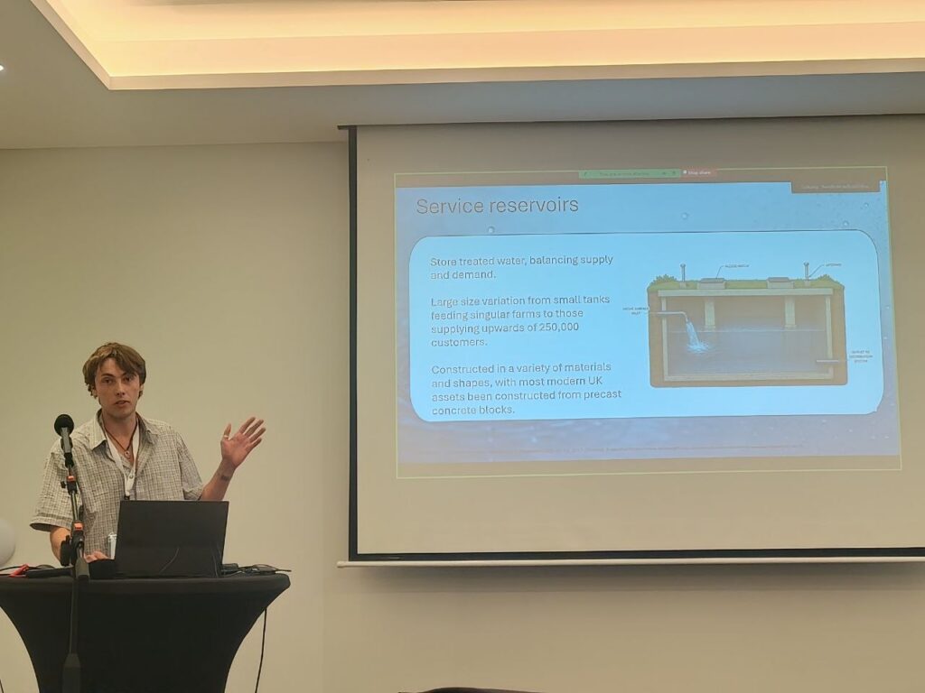 A man presents with a powerpoint presentation behind him