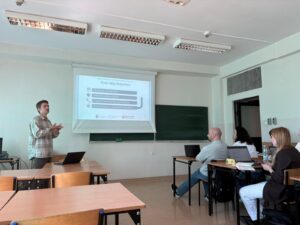 a man delivering a presentation to a room of people set up like a classroom