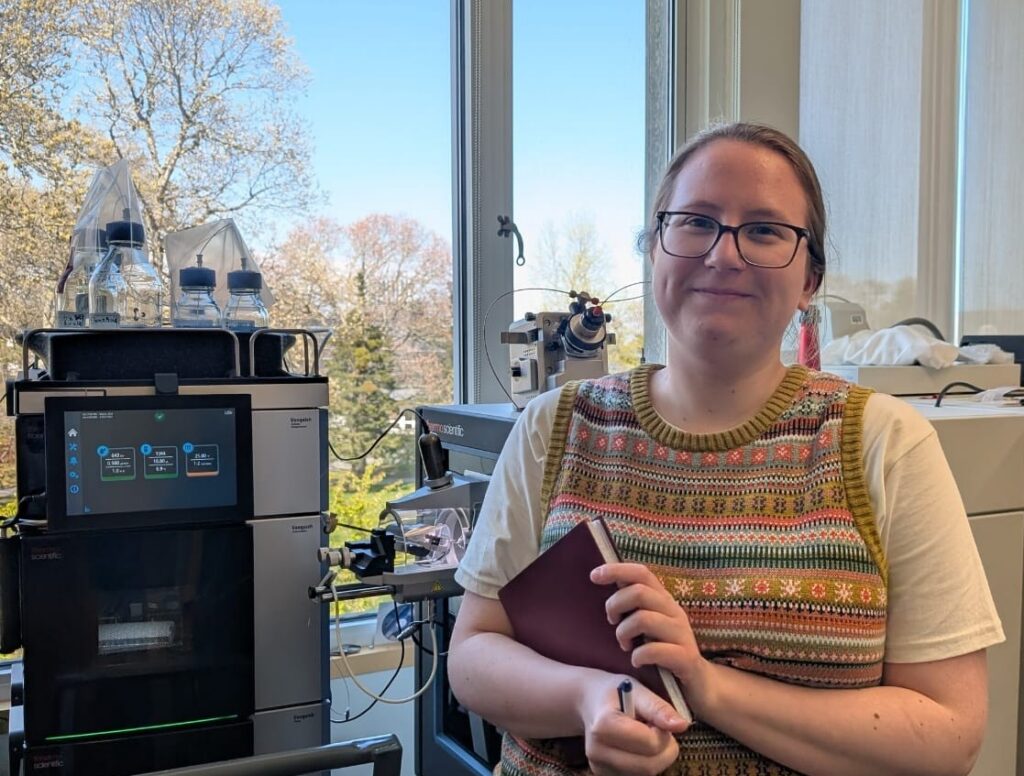 A woman stands in front of laboratory equipment