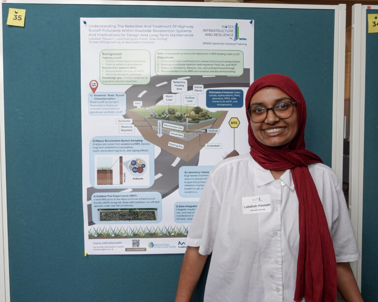 A woman stands smiling next to a scientific poster