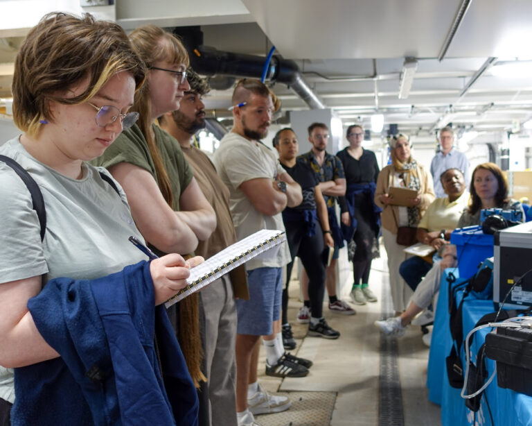 People stood making notes next to an industry demonstration