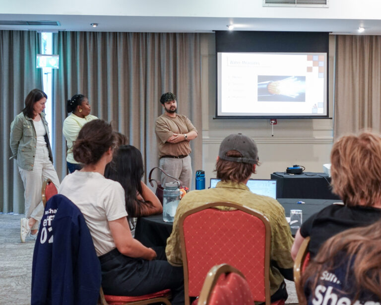 A man presenting to a room of people sat around round table