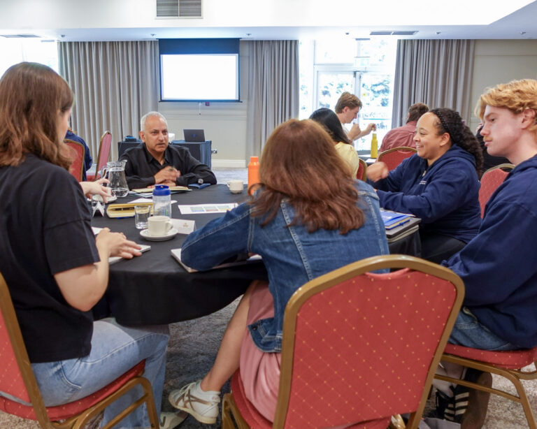 a group of people sat at a round table having a conversation