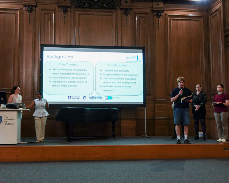 a group of people stand beside a projector screen, presenting to an unseen audience