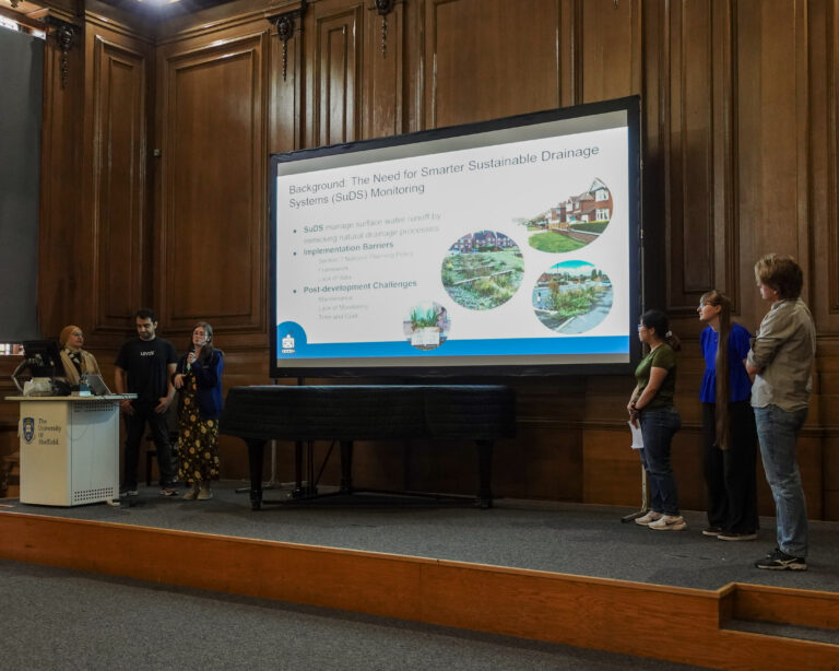 a group of people stand beside a projector screen, presenting to an unseen audience