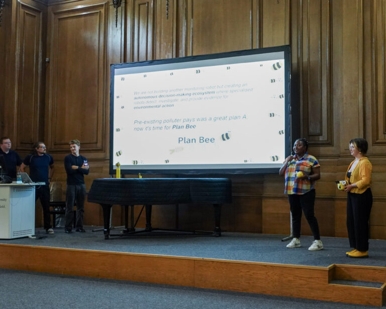a group of people stand beside a projector screen, presenting to an unseen audience