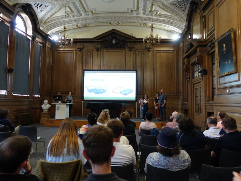 a group of people stand beside a projector screen, presenting to an audience