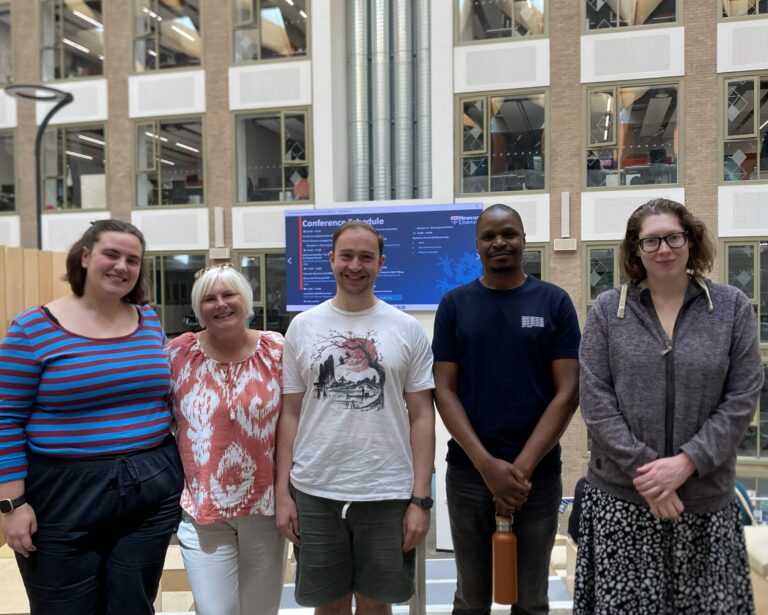 five people stand in a row smiling at the camera